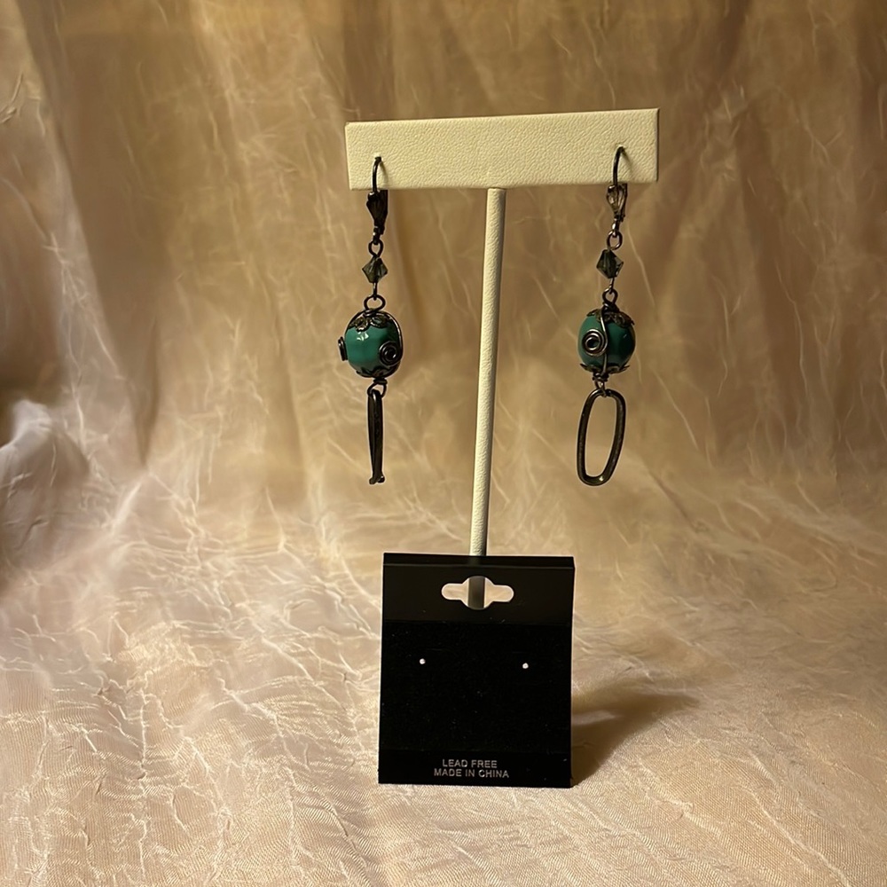 Teal colored stone dangling earrings with scrolled wire latch closure.